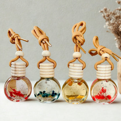 Four glass bottle diffusers with bamboo tops and decorative elements on a neutral background